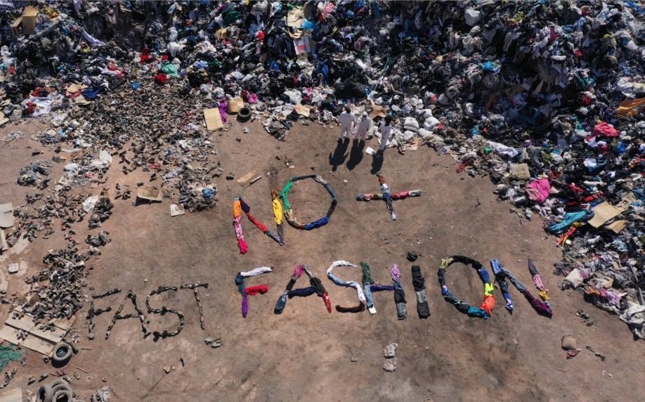 Message "No Fast-Fashion" formé sur la plage à l'aide de vêtements gaspillés